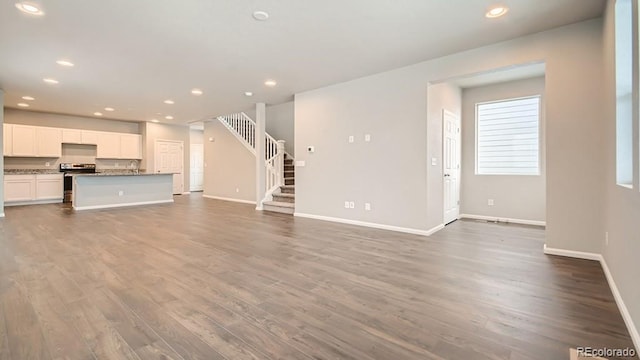 unfurnished living room featuring baseboards, stairway, and recessed lighting