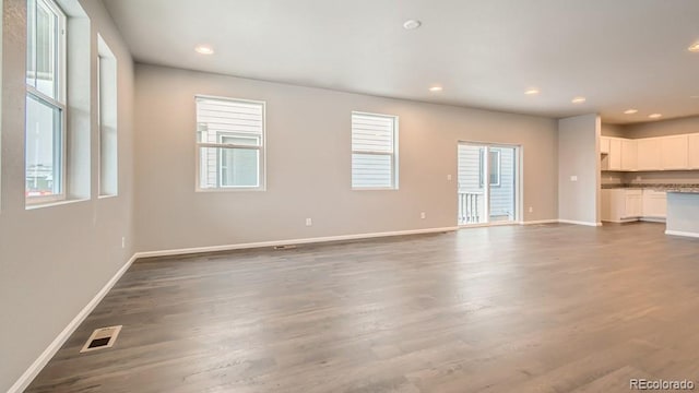 unfurnished living room featuring dark wood-style floors, baseboards, visible vents, and recessed lighting