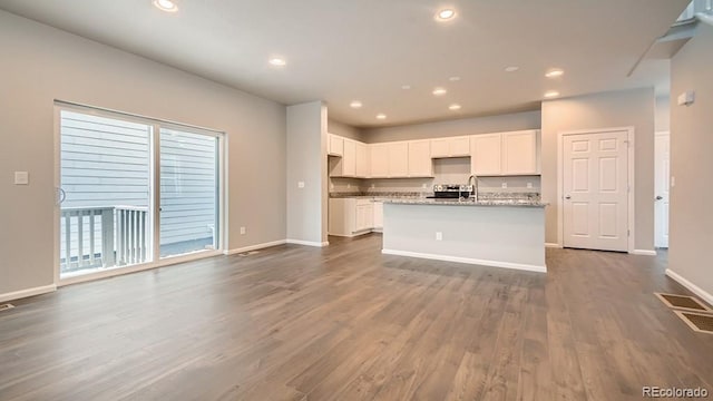 kitchen featuring dark wood-style floors, a center island with sink, recessed lighting, visible vents, and white cabinetry