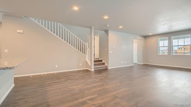 unfurnished living room with recessed lighting, dark wood-style flooring, stairway, and baseboards