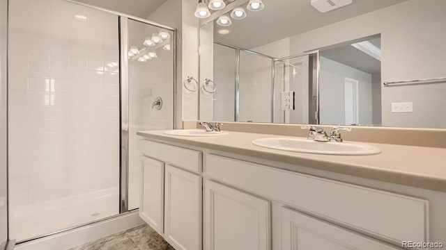 full bath featuring double vanity, a stall shower, and a sink