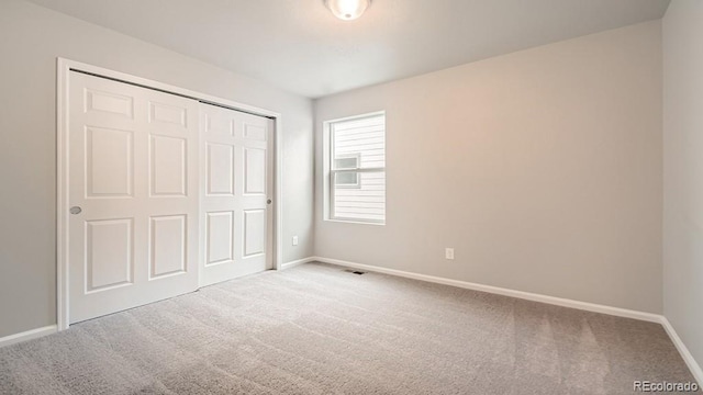 unfurnished bedroom featuring carpet, a closet, and baseboards