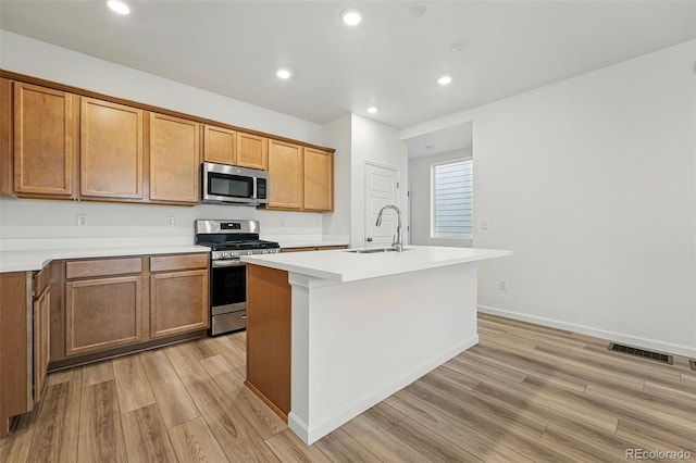 2116 Chambers Rd, Brighton, CO 80601 - kitchen featuring a sink, a kitchen island with sink, light wood-style flooring, light countertops, and appliances with stainless steel finishes