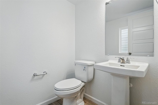 2116 Chambers Rd, Brighton, CO 80601 - half bathroom featuring baseboards, toilet, a sink, and wood finished floors