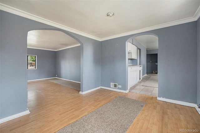2280 S Decatur St, Denver, CO 80219 - empty room with light wood finished floors, arched walkways, baseboards, and crown molding