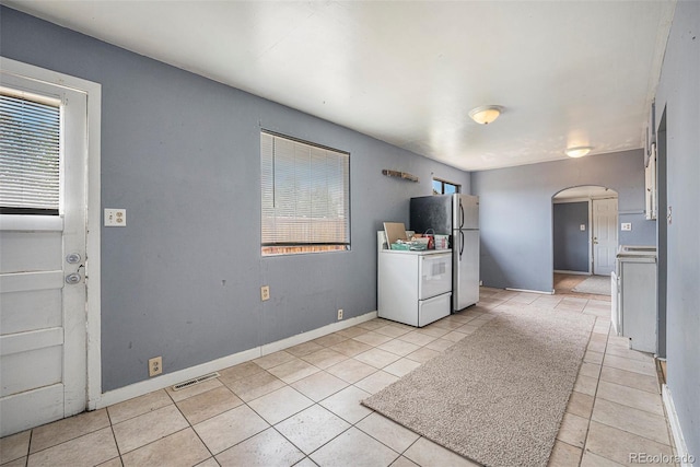 2280 S Decatur St, Denver, CO 80219 - kitchen featuring arched walkways, stove, freestanding refrigerator, light tile patterned flooring, and baseboards