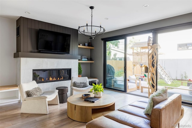 living room with built in features, an inviting chandelier, light hardwood / wood-style floors, and a fireplace