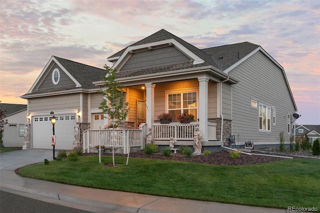 view of front facade with a garage, a porch, driveway, and a front lawn