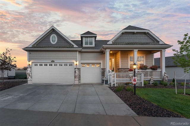 view of front facade featuring concrete driveway, covered porch, a yard, a garage, and stone siding