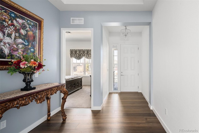 entrance foyer with dark wood-type flooring, baseboards, visible vents, and a chandelier