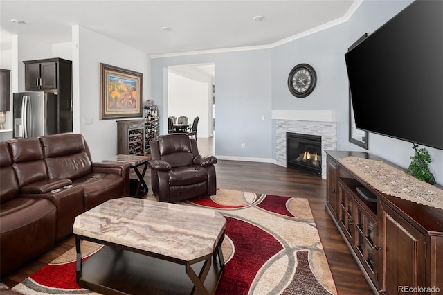 living area featuring dark wood-style floors, a glass covered fireplace, baseboards, and ornamental molding