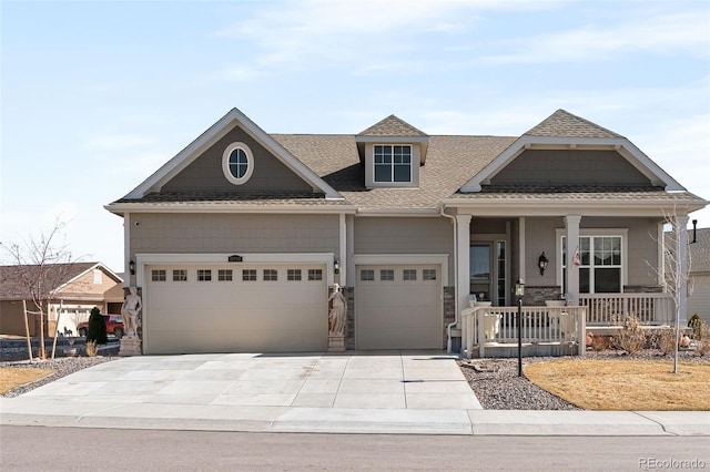 view of front of house featuring driveway, roof with shingles, a porch, an attached garage, and stone siding