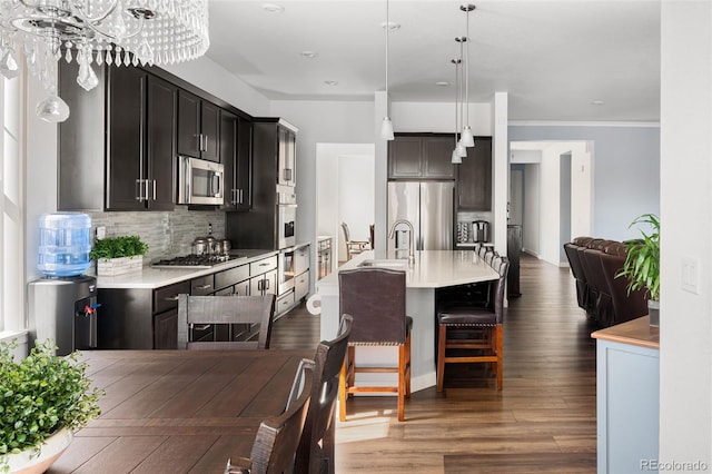 kitchen with dark wood-type flooring, light countertops, decorative backsplash, stainless steel appliances, and a sink