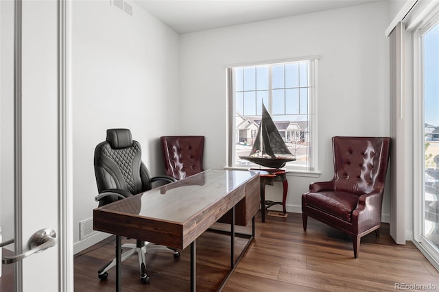 office space with wood finished floors, visible vents, and baseboards