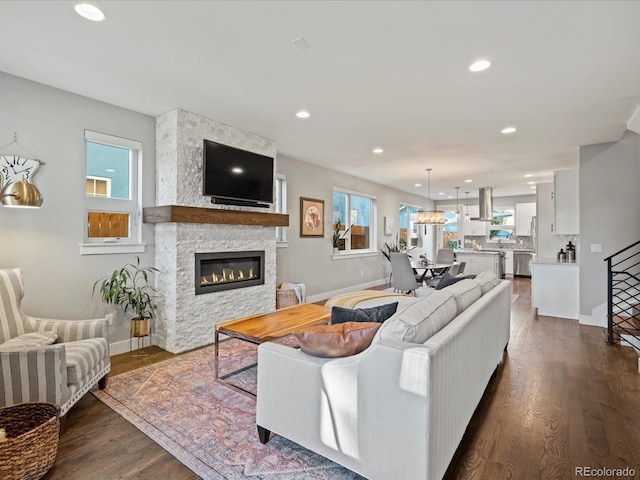 living room featuring a stone fireplace and dark hardwood / wood-style floors