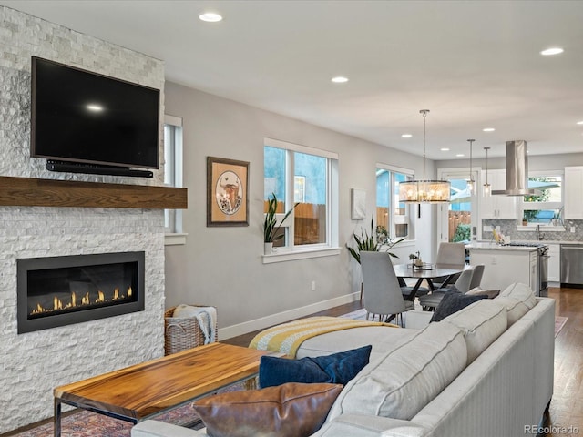 living room with a stone fireplace, a healthy amount of sunlight, and hardwood / wood-style flooring