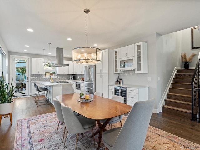 dining space with hardwood / wood-style flooring, beverage cooler, and an inviting chandelier