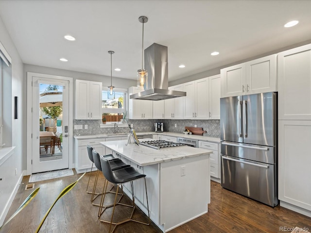 kitchen featuring hanging light fixtures, a kitchen island, appliances with stainless steel finishes, island range hood, and white cabinetry