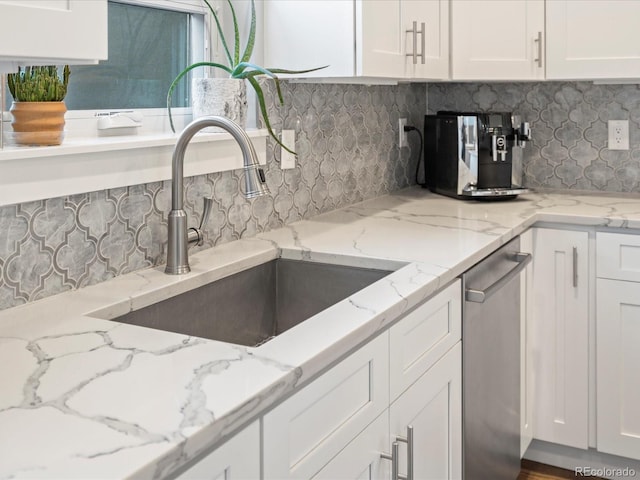 kitchen featuring backsplash, white cabinets, sink, stainless steel dishwasher, and light stone counters