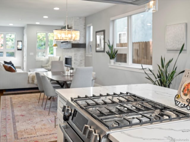 kitchen with pendant lighting, light stone countertops, and stainless steel gas range