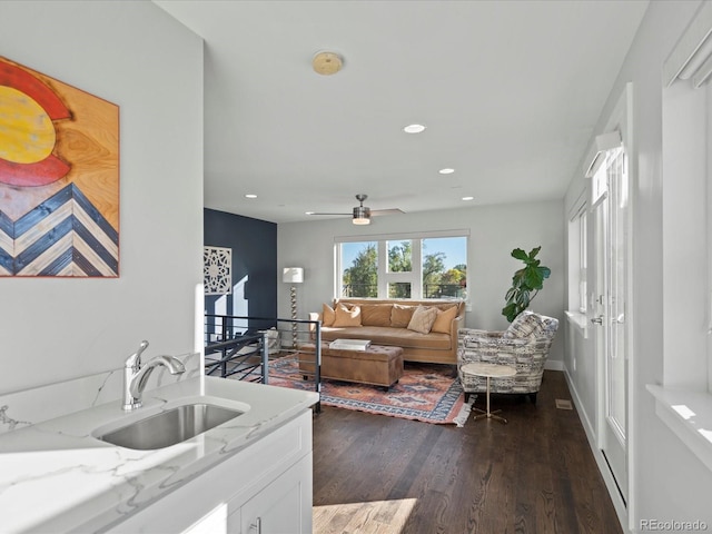 living room featuring dark hardwood / wood-style flooring, ceiling fan, and sink