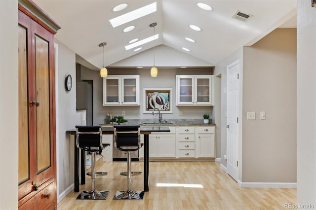 901 S Leyden St, Denver, CO 80224 - kitchen with a skylight, lofted ceiling, glass insert cabinets, light wood-style flooring, and pendant lighting