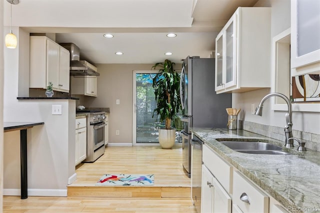 901 S Leyden St, Denver, CO 80224 - kitchen featuring appliances with stainless steel finishes, white cabinets, light wood-type flooring, recessed lighting, and wall chimney range hood