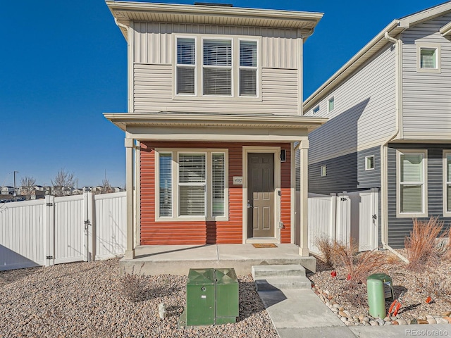 view of front of home featuring board and batten siding, fence, and a gate