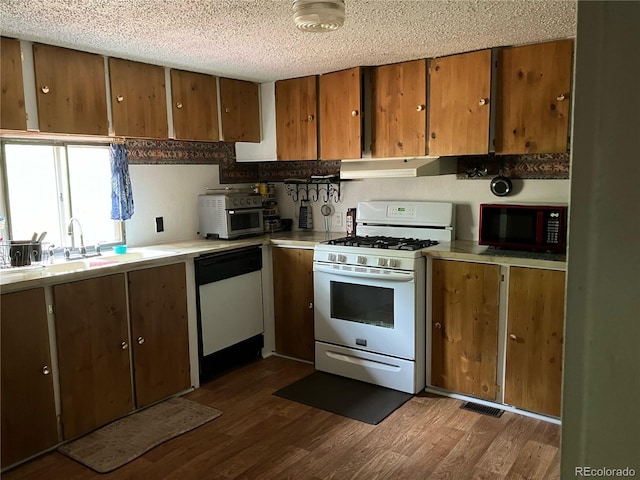 kitchen with sink, a textured ceiling, dark wood-type flooring, and white appliances