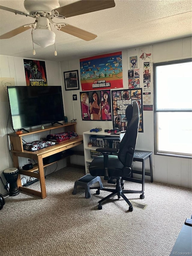 carpeted office space with ceiling fan and a textured ceiling