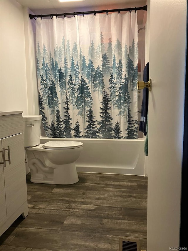 full bathroom featuring hardwood / wood-style flooring, toilet, shower / bath combo with shower curtain, and vanity