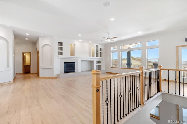 interior space with baseboards, wood finished floors, an upstairs landing, built in shelves, and recessed lighting