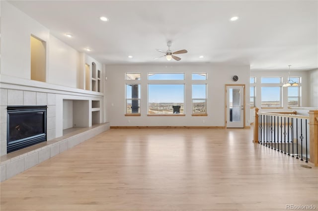 unfurnished living room with built in shelves, a fireplace, light wood-style flooring, and a healthy amount of sunlight