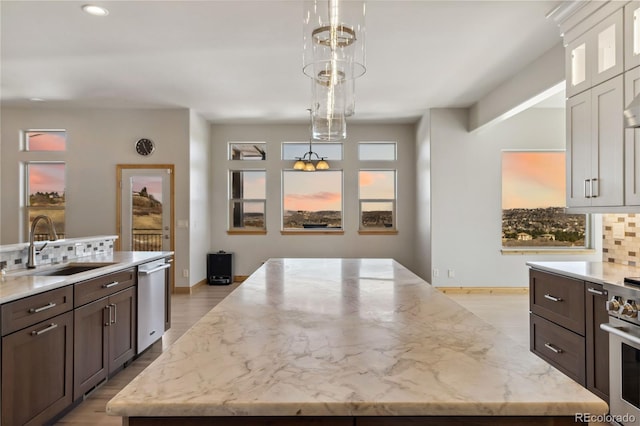 kitchen with backsplash, appliances with stainless steel finishes, a healthy amount of sunlight, a kitchen island, and a sink