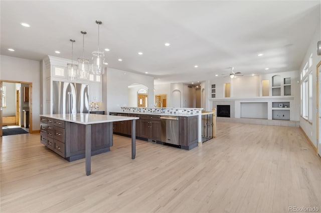 kitchen featuring light countertops, appliances with stainless steel finishes, a large island, and dark brown cabinets