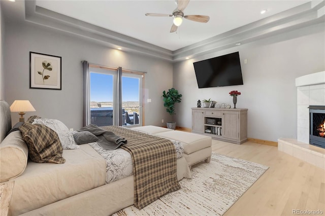 bedroom with ceiling fan, a tile fireplace, recessed lighting, wood finished floors, and baseboards