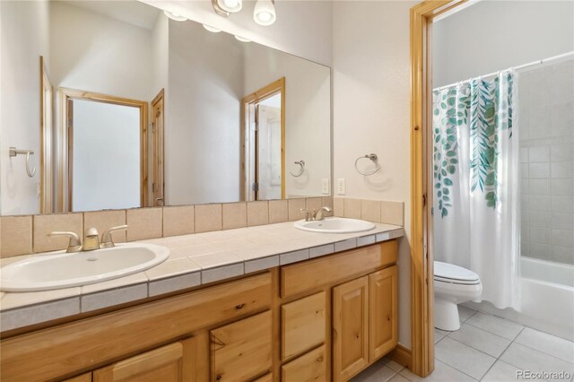 full bathroom with double vanity, a sink, toilet, and tile patterned floors