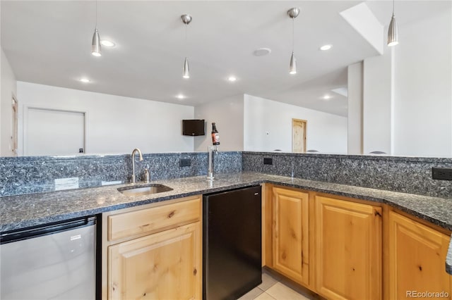 kitchen with dark stone counters, dishwasher, hanging light fixtures, fridge, and a sink