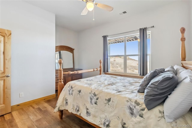 bedroom featuring baseboards, visible vents, ceiling fan, and wood finished floors