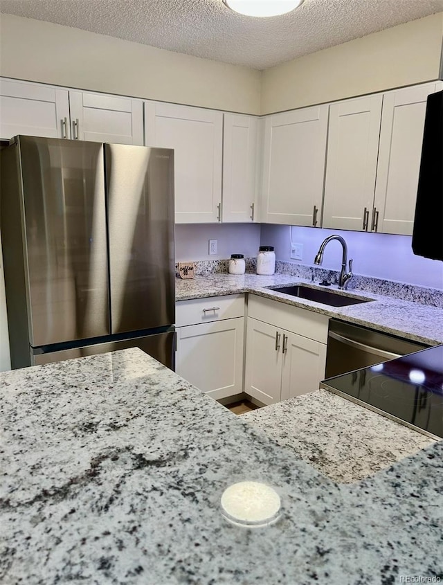 10251 W 44th Ave Unit 3-204, Wheat Ridge, CO 80033 - kitchen featuring freestanding refrigerator, a sink, a textured ceiling, white cabinetry, and light stone counters
