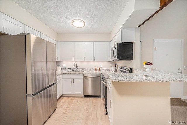 10251 W 44th Ave Unit 3-204, Wheat Ridge, CO 80033 - kitchen with stainless steel appliances, a sink, a peninsula, light wood-style floors, and white cabinets