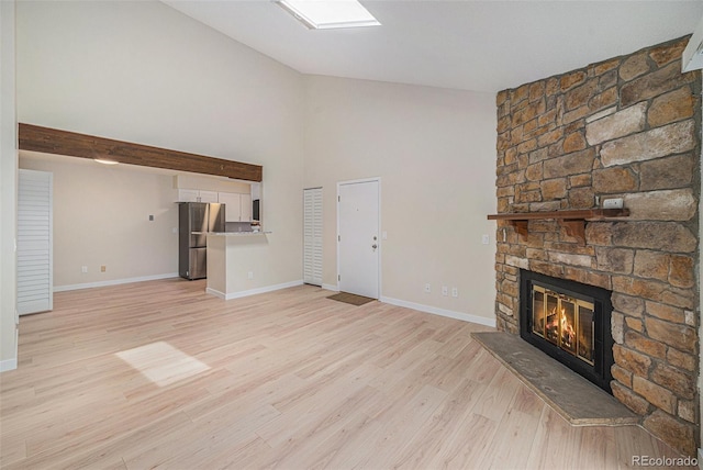 10251 W 44th Ave Unit 3-204, Wheat Ridge, CO 80033 - unfurnished living room with a stone fireplace, light wood-type flooring, high vaulted ceiling, and baseboards