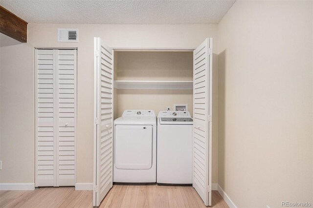 10251 W 44th Ave Unit 3-204, Wheat Ridge, CO 80033 - laundry area featuring washing machine and dryer, light wood-type flooring, baseboards, and a textured ceiling