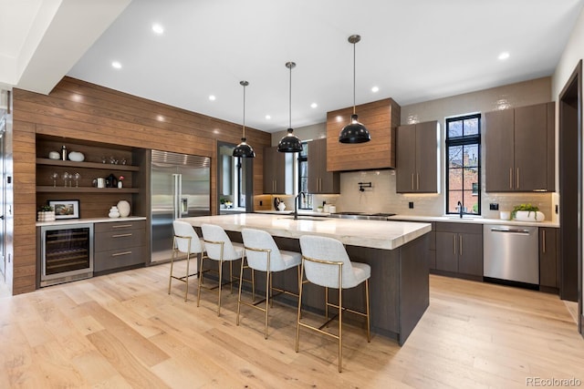 1100 S Elizabeth St, Denver, CO 80210 - kitchen featuring appliances with stainless steel finishes, a wealth of natural light, light wood-style flooring, and wine cooler