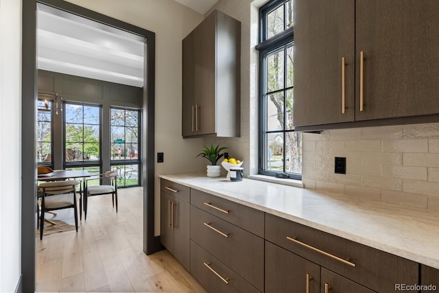 1100 S Elizabeth St, Denver, CO 80210 - kitchen with light stone counters, light wood-style flooring, dark brown cabinetry, and tasteful backsplash