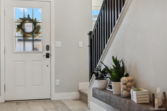 foyer entrance with stairway and baseboards