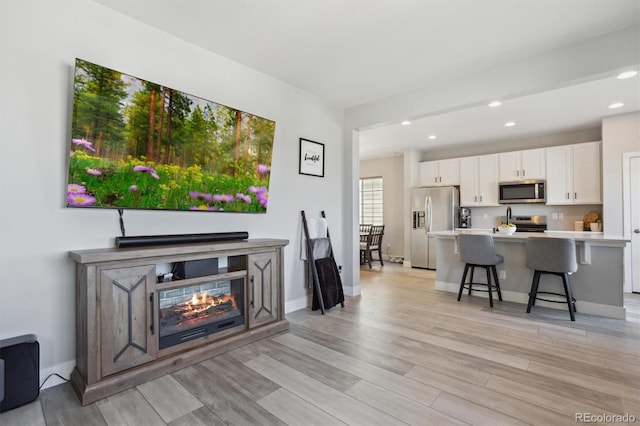 living area with recessed lighting, light wood-type flooring, and baseboards