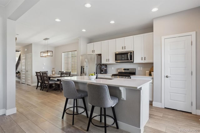 kitchen featuring light wood-style flooring, stainless steel appliances, a kitchen bar, and a sink