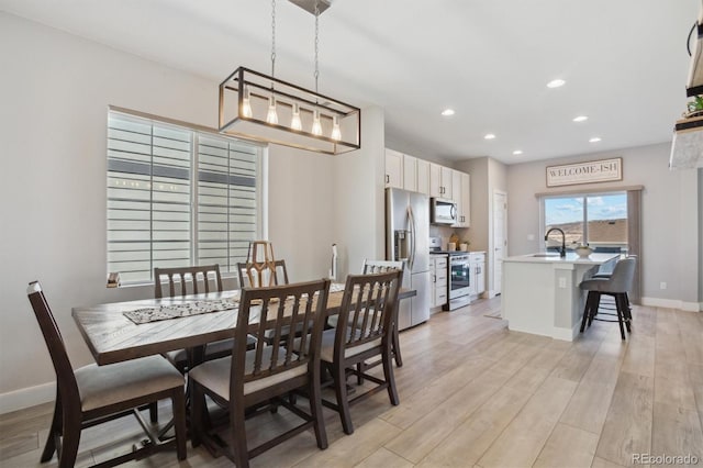 dining room with recessed lighting, baseboards, and light wood-style flooring