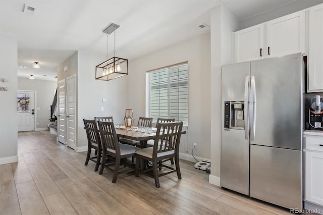 dining room featuring plenty of natural light, an inviting chandelier, light wood-type flooring, and visible vents